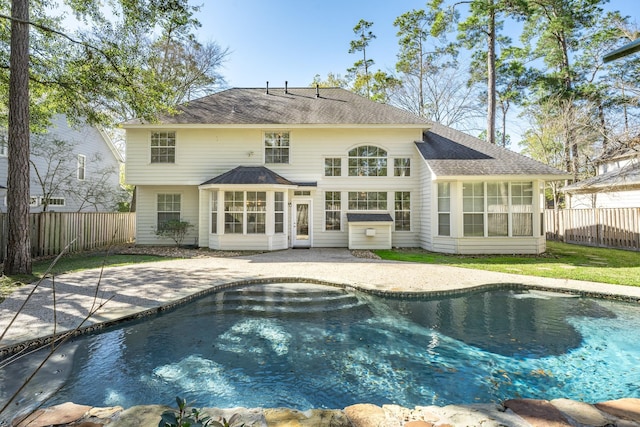 back of property with a fenced in pool, a sunroom, and a patio