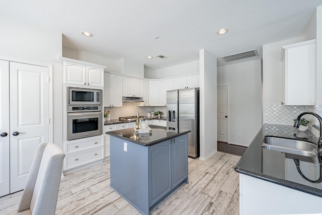 kitchen featuring white cabinetry, sink, dark stone countertops, a center island, and stainless steel appliances