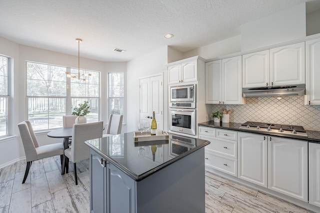 kitchen featuring pendant lighting, appliances with stainless steel finishes, tasteful backsplash, a textured ceiling, and white cabinets