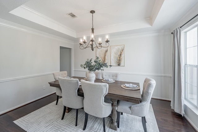 dining room featuring crown molding, a notable chandelier, a tray ceiling, and dark wood-type flooring