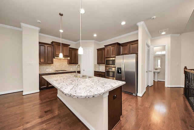 kitchen featuring tasteful backsplash, stainless steel appliances, sink, decorative light fixtures, and an island with sink