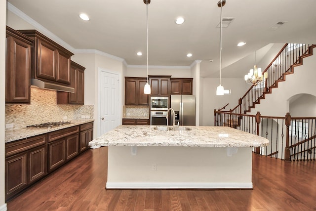 kitchen featuring pendant lighting, a notable chandelier, stainless steel appliances, and a large island with sink