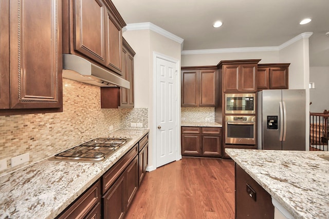 kitchen featuring stainless steel appliances, tasteful backsplash, light stone counters, dark hardwood / wood-style floors, and crown molding