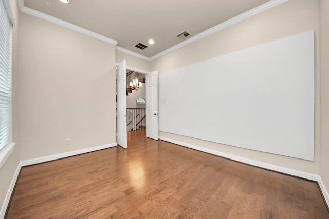 empty room featuring crown molding, hardwood / wood-style floors, and a notable chandelier