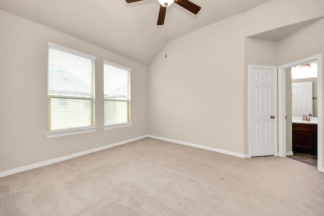 unfurnished bedroom with ensuite bath, ceiling fan, sink, light colored carpet, and lofted ceiling