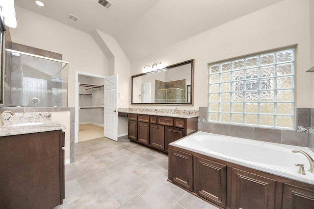 bathroom with tile patterned flooring, vanity, separate shower and tub, and vaulted ceiling