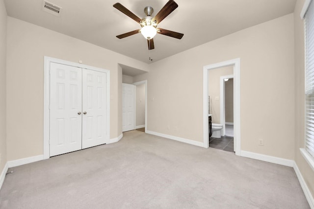 unfurnished bedroom with ceiling fan, light colored carpet, connected bathroom, and a closet