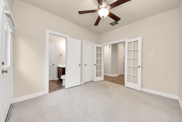 unfurnished bedroom with ensuite bath, ceiling fan, carpet floors, and french doors