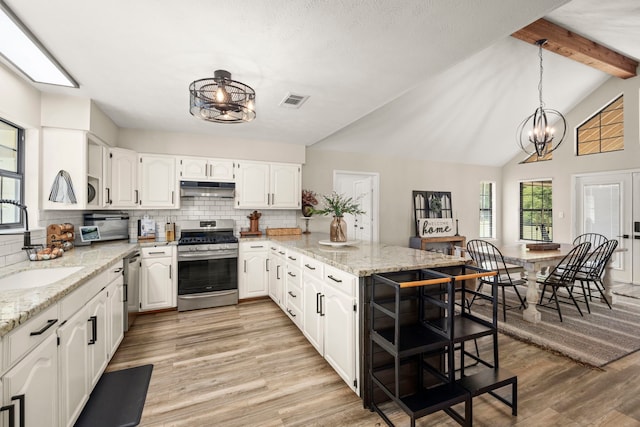 kitchen featuring white cabinets, lofted ceiling with beams, appliances with stainless steel finishes, and a notable chandelier