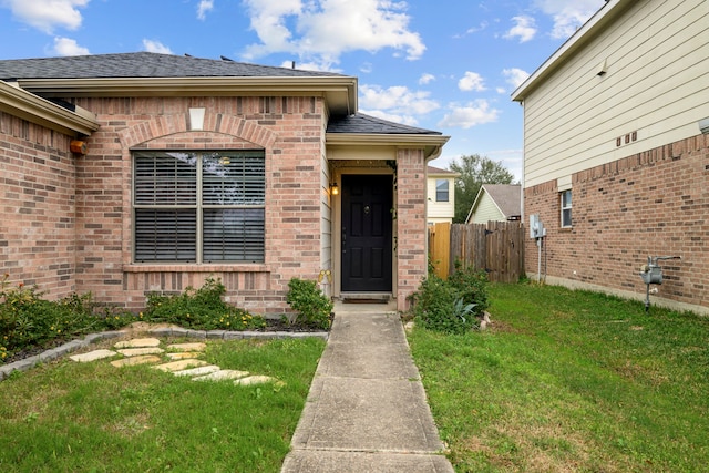 view of exterior entry featuring a lawn