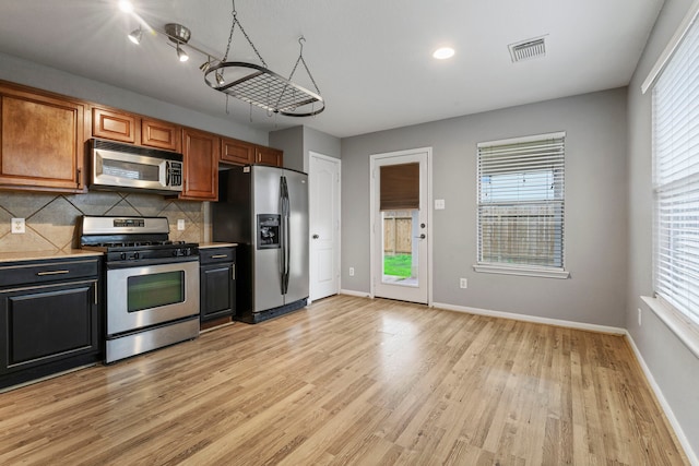 kitchen with light wood-type flooring, backsplash, stainless steel appliances, and track lighting