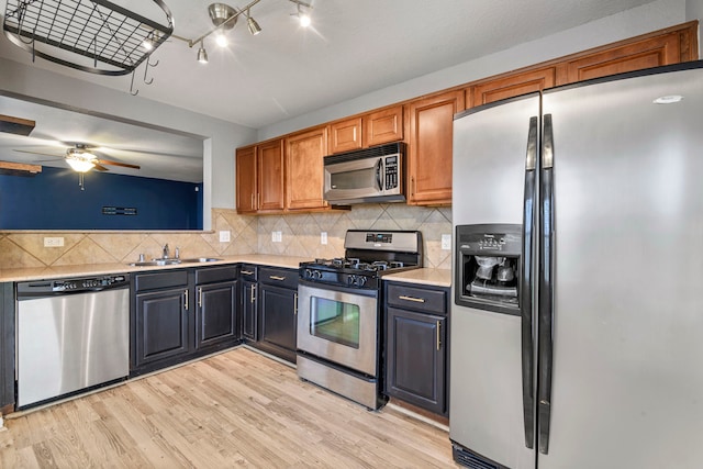 kitchen with ceiling fan, sink, stainless steel appliances, tasteful backsplash, and light wood-type flooring