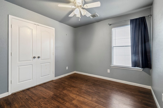 unfurnished bedroom with ceiling fan, dark hardwood / wood-style floors, and a closet