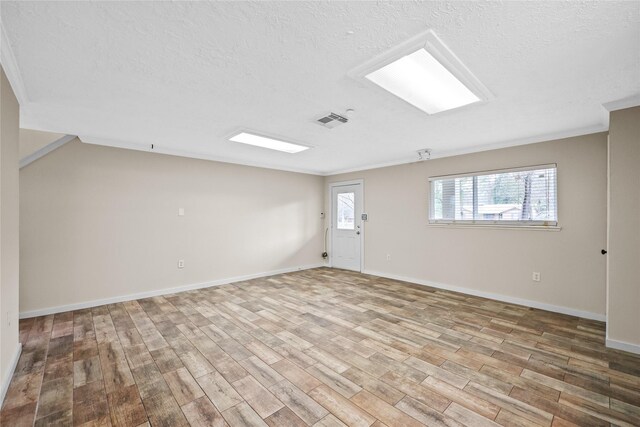 unfurnished room with a textured ceiling and light hardwood / wood-style floors