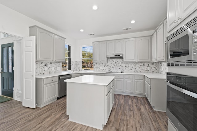 kitchen with gray cabinetry, decorative backsplash, a center island, and appliances with stainless steel finishes