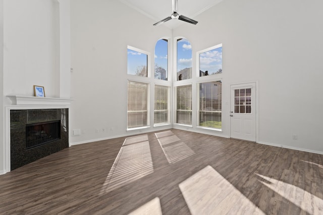 unfurnished living room featuring dark hardwood / wood-style flooring, ceiling fan, a fireplace, and a high ceiling