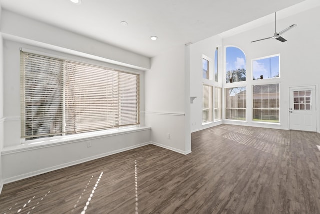 unfurnished living room with ceiling fan, a healthy amount of sunlight, and dark wood-type flooring