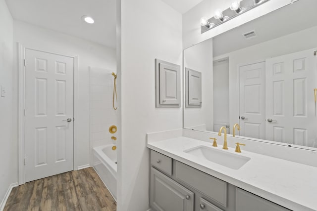 bathroom with hardwood / wood-style floors, vanity, and tiled shower / bath