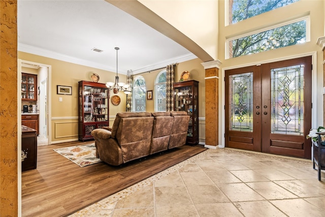 entryway featuring a chandelier, french doors, and crown molding