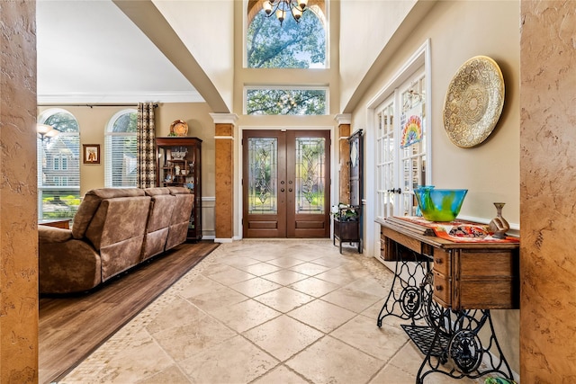 foyer featuring french doors, ornamental molding, a high ceiling, and an inviting chandelier