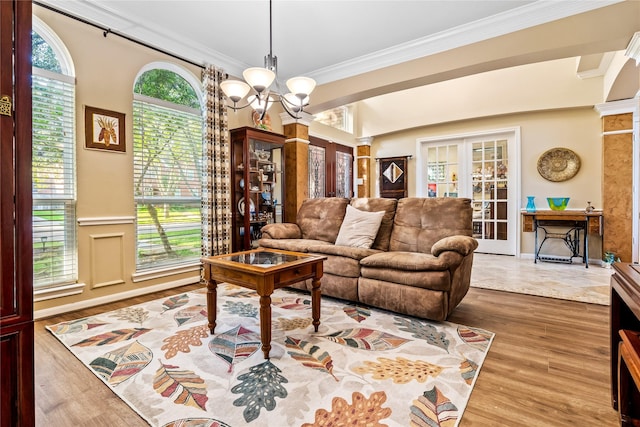 living room featuring a healthy amount of sunlight, wood-type flooring, crown molding, and an inviting chandelier