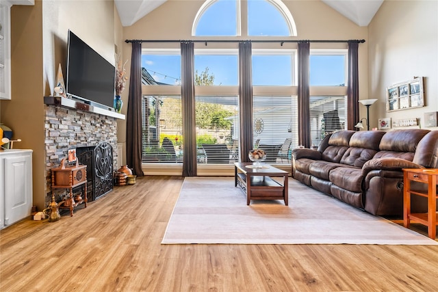 living room featuring a fireplace, high vaulted ceiling, and light hardwood / wood-style flooring