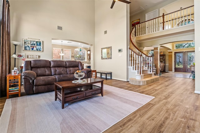 living room with a healthy amount of sunlight, french doors, wood-type flooring, and a high ceiling