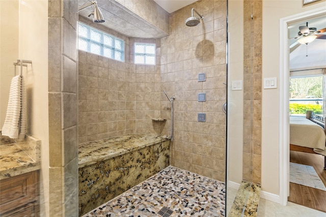 bathroom with ceiling fan, tiled shower, and a wealth of natural light