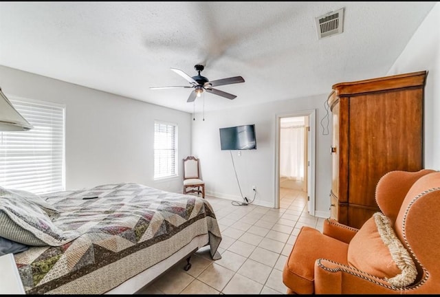 bedroom featuring ceiling fan, light tile patterned flooring, and a textured ceiling