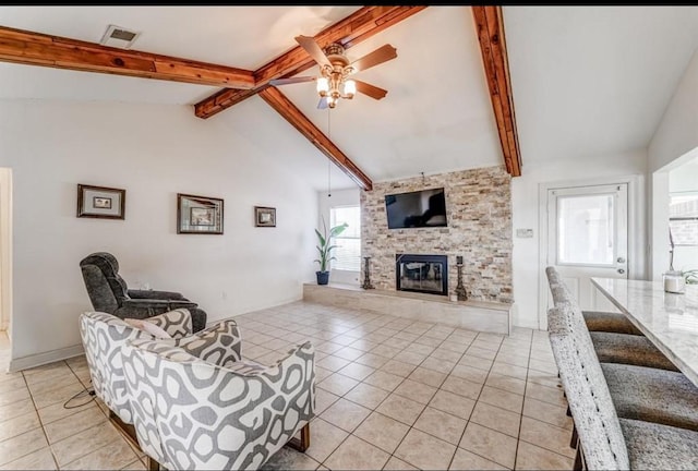 tiled living room with ceiling fan, beam ceiling, a stone fireplace, and high vaulted ceiling