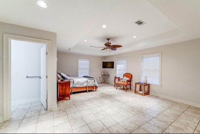 bedroom featuring ceiling fan, a raised ceiling, and light tile patterned floors