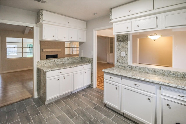 kitchen featuring decorative backsplash, white cabinetry, dark wood-type flooring, and light stone counters