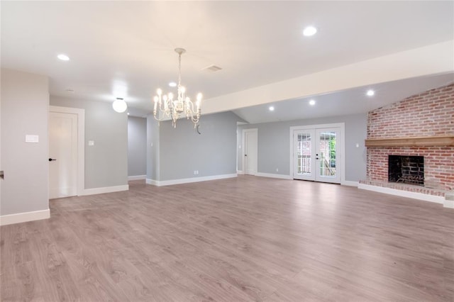 unfurnished living room with french doors, an inviting chandelier, a fireplace, light hardwood / wood-style floors, and lofted ceiling