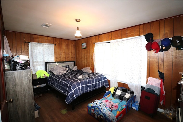 bedroom featuring wooden walls and dark wood-type flooring