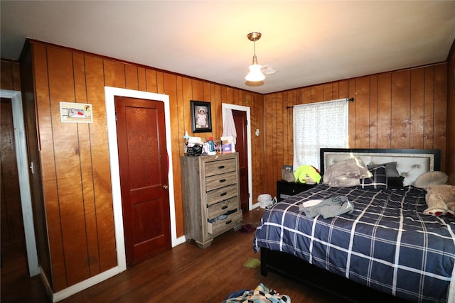 bedroom with dark hardwood / wood-style floors and wooden walls