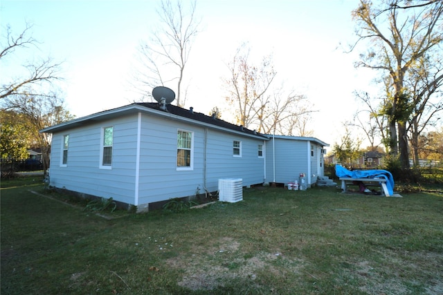 back of house featuring a lawn and central air condition unit