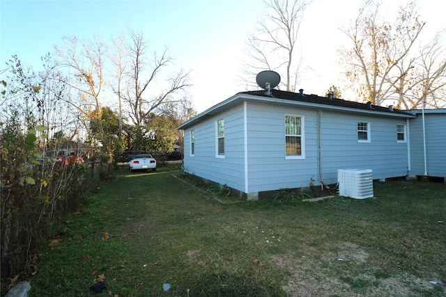 view of side of home featuring central air condition unit and a yard