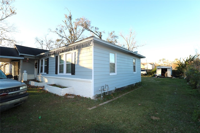 view of side of home with a yard and a storage shed