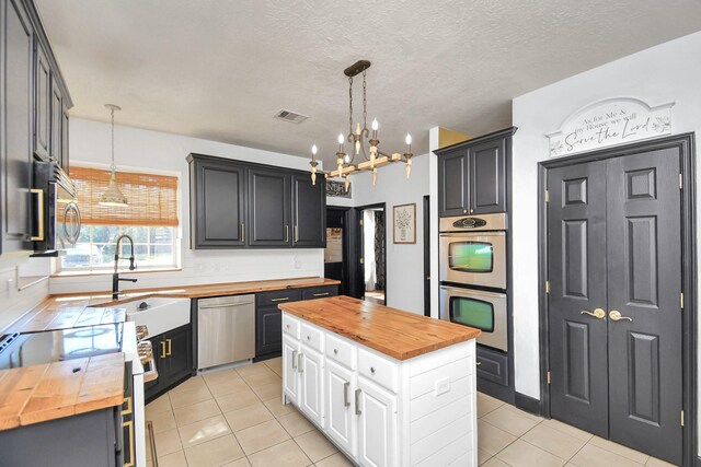 kitchen with white cabinets, stainless steel appliances, a kitchen island, and butcher block counters