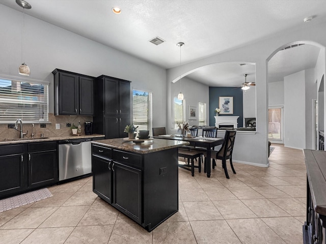 kitchen with dishwasher, a center island, dark stone counters, and sink