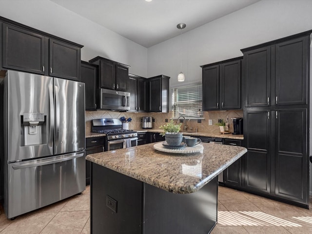 kitchen featuring light tile patterned floors, a kitchen island, decorative light fixtures, and appliances with stainless steel finishes