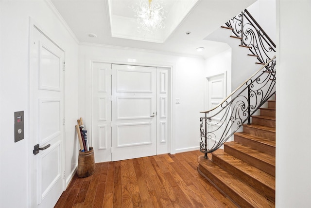 foyer entrance featuring hardwood / wood-style floors, an inviting chandelier, and ornamental molding