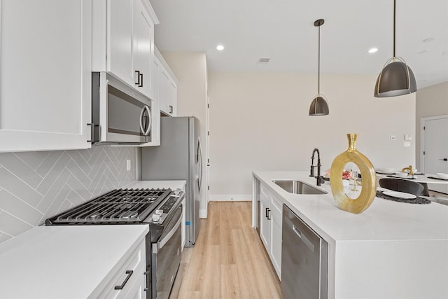 kitchen featuring appliances with stainless steel finishes, backsplash, sink, white cabinetry, and hanging light fixtures