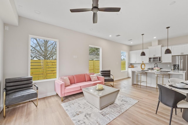 living room with light hardwood / wood-style floors and ceiling fan