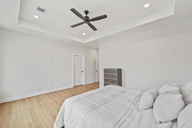 bedroom featuring hardwood / wood-style flooring, ceiling fan, and a tray ceiling