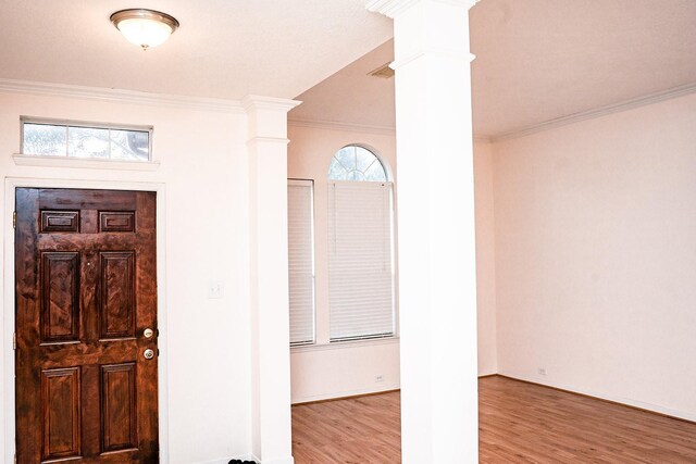 entryway featuring light wood-type flooring, decorative columns, plenty of natural light, and crown molding