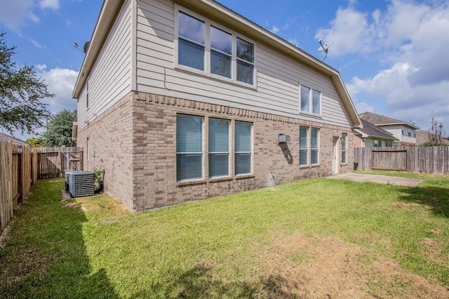 rear view of property with a lawn, central air condition unit, and a patio