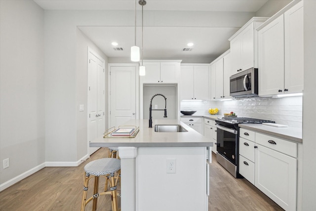 kitchen with white cabinetry, sink, a center island with sink, and appliances with stainless steel finishes