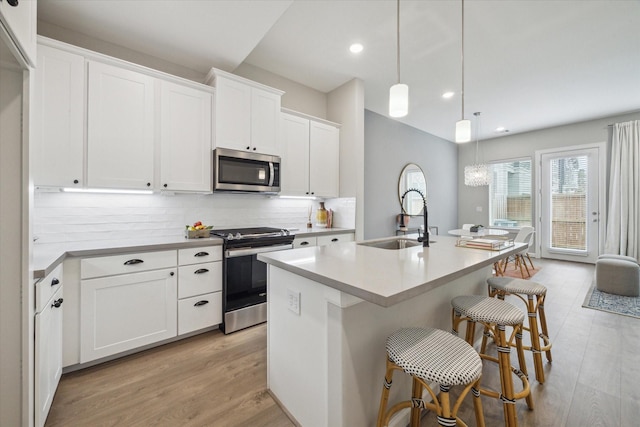 kitchen featuring a center island with sink, sink, white cabinets, and stainless steel appliances