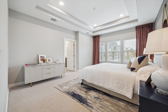 bedroom with a tray ceiling and light carpet